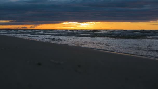 Las olas de agua que vienen en primer plano en la orilla del mar en la luz dramática épica del atardecer — Vídeos de Stock