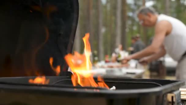 Jogando mais carvão na guelra churrasco fogo pit mão closeup — Vídeo de Stock