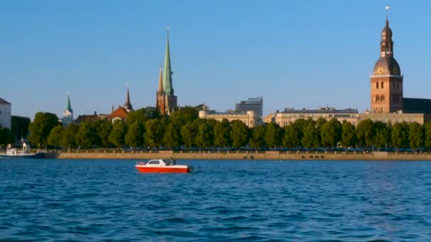 Riga Cidade Velha panorama fundo com pequeno barco vermelho passando por um rio — Vídeo de Stock