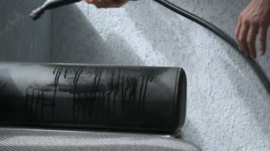 El kanepe bir buharlı temizleyici ile temizliyor. Ev temizlik kavramı.