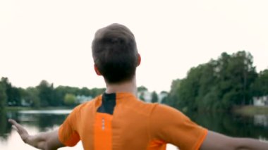 Genç yükseltir hava eller, yavaş yavaş froward daha yakın göle yürüyor