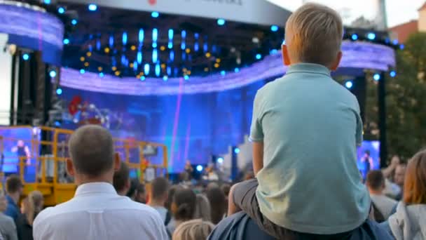 Kind sitzt Vater im Nacken und sieht Live-Rockmusik auf Open-Air-Stadtfest — Stockvideo