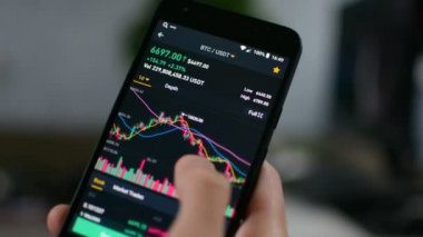 İşadamı cep telefonu ekranında dijital döviz grafiği, kripto para birimi gelecekteki fiyat öngörüsü konseptini kontrol ediyor