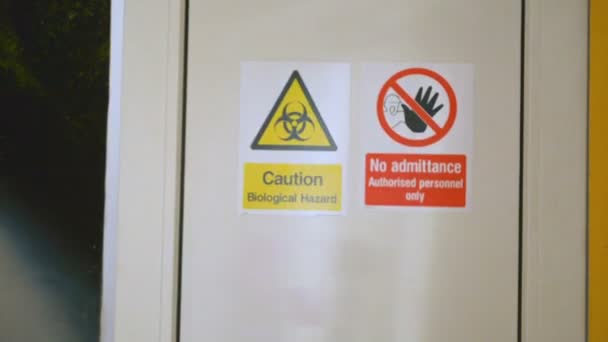 Scientist enters and leaves bio laboratory, warning sign Biological hazard on the door — Stock Footage Scientist enters and leaves bio laboratory, warning sign Biological hazard on the door Royalty Free Stock Footage