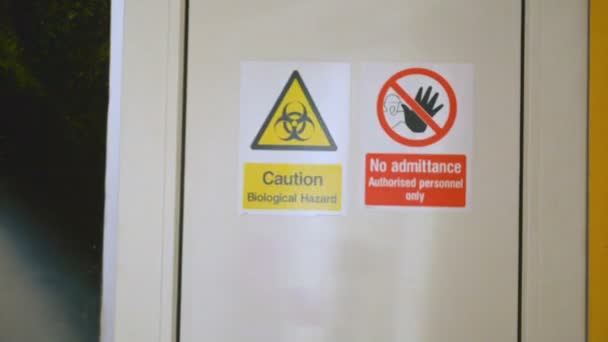 Scientist enters and leaves bio laboratory, warning sign Biological hazard on the door — Stock Video