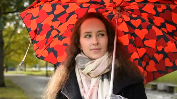 Hermosa dama con gran paraguas rojo caminando en el parque en otoño dorado — Vídeos de Stock