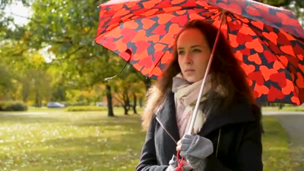 wunderschöne Dame mit großem roten Regenschirm spaziert im Park im goldenen Herbst