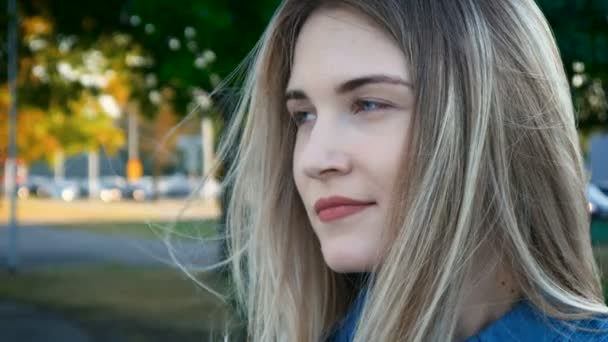 Retrato de cerca de una hermosa mujer con hermosos ojos azules y cabello largo en el parque — Vídeo de stock