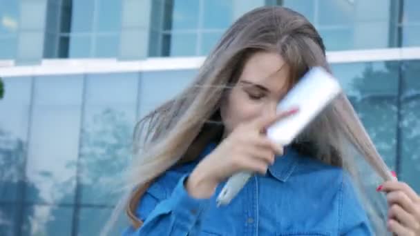 Charmante dame essayant de peigner brosser ses cheveux dans un vent violent — Video