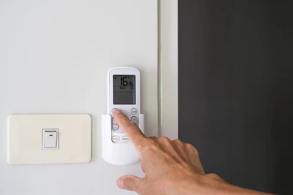 Man hand turn on air condition remote switch — Stock Photo, Image