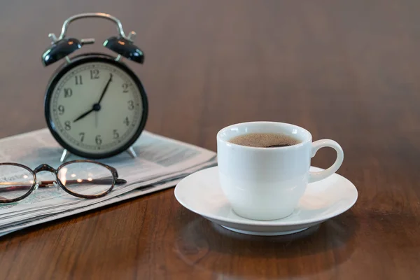 Чашка горячего кофе и старинные часы газеты очки для чтения на бр. — стоковое фото