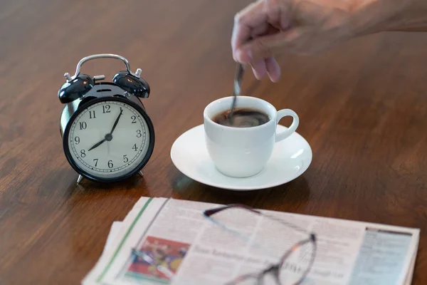 Sıcak kahve fincanı ve vintage saat gazete okuma bardakları br — Stok fotoğraf