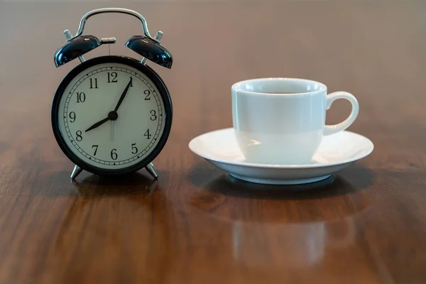 Varm kaffekopp og årgangsklokke klokka åtte om morgenen – stockfoto