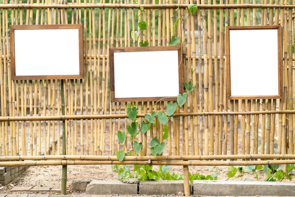 Marco de fotos de madera blanco en blanco sobre fondo de pared de bambú —  Fotos de Stock