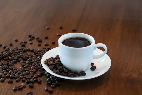 Hot coffee cup with roasted coffee beans on wood table — Stock Photo, Image