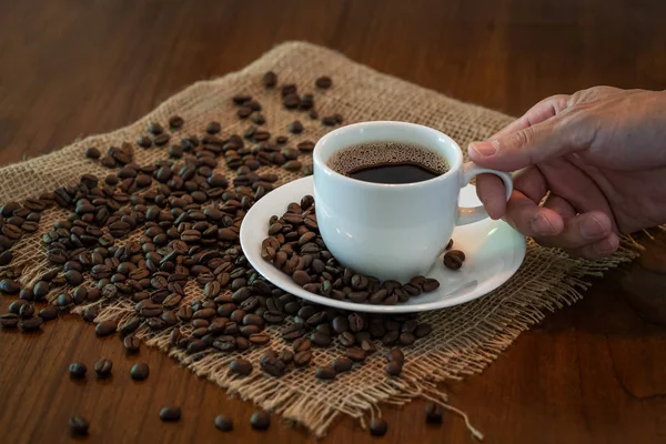 Гаряча чашка кави зі смаженими кавовими зернами на дерев'яному столі — стокове фото