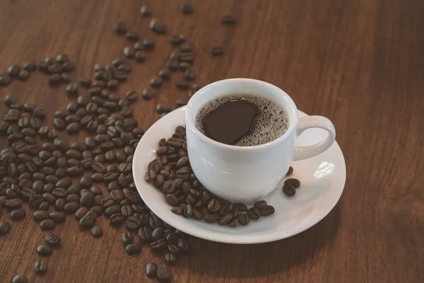 Гаряча чашка кави з кавовими зернами на дерев'яному столі — стокове фото