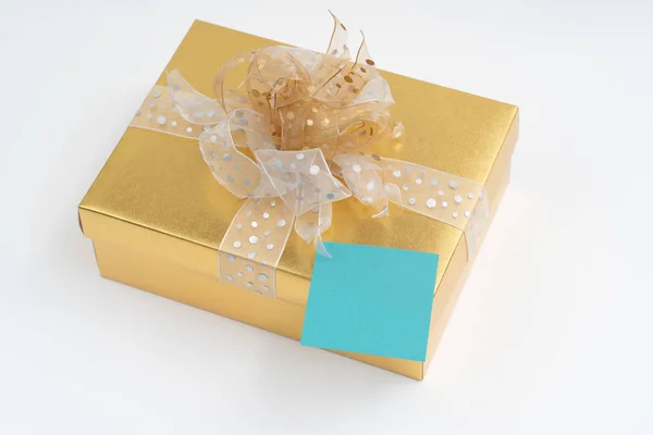 Blank adhesive note on gold gift box on white background — Stock Photo, Image