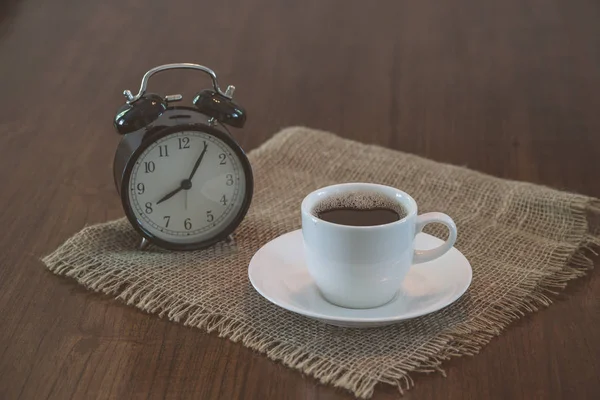 Чашка горячего кофе и винтажные часы — стоковое фото