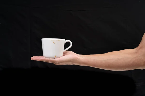 Чоловік тримає чашку білої кави на чорному тлі — стокове фото