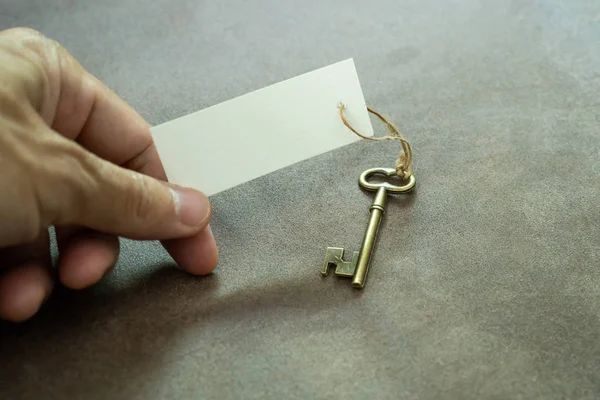 Vecchia chiave vintage in ottone bianco mano in possesso di etichetta bianca — Foto Stock