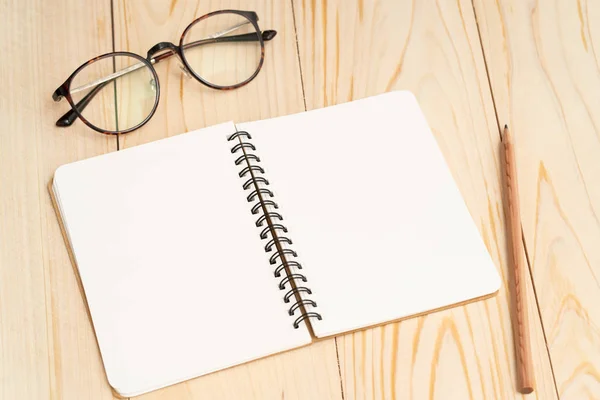 Cuaderno en blanco y vasos de lectura sobre mesa de madera —  Fotos de Stock