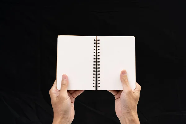 Man hand hålla tom anteckningsbok på svart bakgrund — Stockfoto