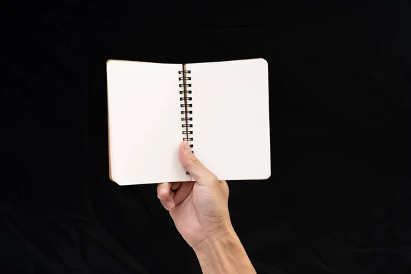 Homem mão segurando notebook em branco no fundo preto — Fotografia de Stock