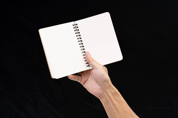 Homem mão segurando notebook em branco no fundo preto — Fotografia de Stock