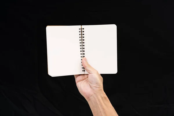 Mann hält leeres Notizbuch auf schwarzem Hintergrund — Stockfoto