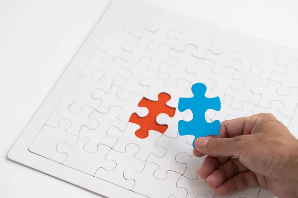 Main tenant pièce bleue puzzle avec tenue rouge puzzle fond — Photo
