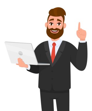 Genç iş adamı yeni dizüstü bilgisayar cihazını tutuyor / gösteriyor ve işaret ediyor ya da el parmağıyla bir numarayı gösteriyor. Modern yaşam tarzı, dijital teknoloji eğilimi, aygıt.