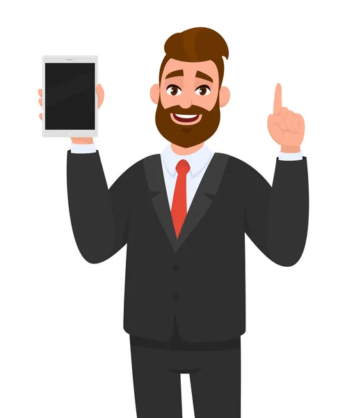 Sonriente joven hombre de negocios barbudo mostrando / sosteniendo la pantalla en blanco de una nueva pantalla de tableta y señalando / señalando el dedo índice de la mano hacia arriba. Ilustración moderna del concepto de tecnología digital en dibujos animados . — Vector de stock