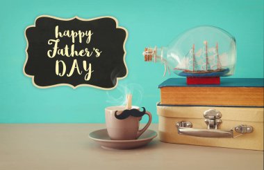 Fincan kahve, eski kitap, eski çanta kutu ve tekne ahşap masa üzerinde şişede görüntüsü. Babalar günü kavramı