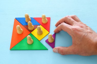 tangram bulmacanın blok ahşap masa, insan kaynakları ve yönetim kavramı üzerinde satranç figürleri ile görüntü