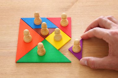 tangram bulmacanın blok ahşap masa, insan kaynakları ve yönetim kavramı üzerinde satranç figürleri ile görüntü.