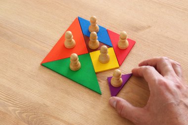 tangram bulmacanın blok ahşap masa, insan kaynakları ve yönetim kavramı üzerinde satranç figürleri ile görüntü