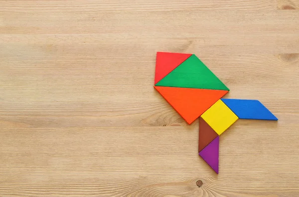 Raketa z tangram puzzle o modré pastelové dřevěné pozadí. — Stock fotografie