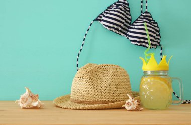 Görüntü taze limonata içmek tatlı ananas şekli cam bikini mayo ve plaj fedora şapka yanındaki bükülmüş saman ile ahşap masa üzerinde