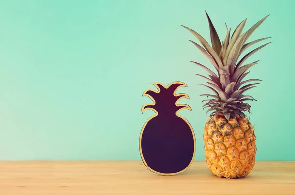 Piña sobre mesa de madera junto a pizarra vacía. Playa y tema tropical . — Foto de Stock