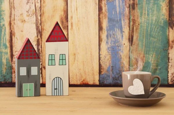 Image of hot coffee or tea and cute houses over wooden table. Father's day concept