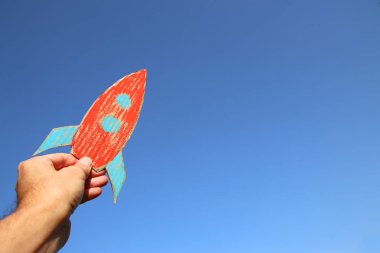 bir roket gökyüzüne karşı tutan erkek el görüntüsü. hayal gücü ve başarı kavramı