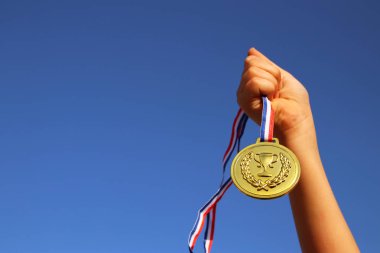 çocuk elini kaldırdı, holding altın madalya gökyüzü karşı. Eğitim, başarı, başarı, ödül ve zafer kavramı