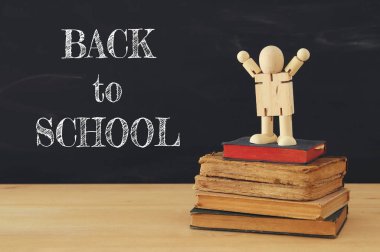 kitapların bir yığınına bir ahşap şekil ayakta görüntüsü. Başarı, eğitim ve okula geri kavramı