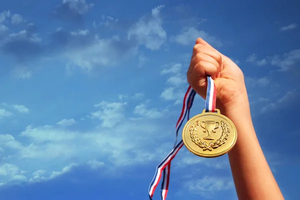 Main Enfant Levée Tenant Médaille Contre Ciel Éducation Réussite Réalisation — Photo