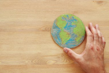 ahşap masa üzerinde dünya küre tutan adam el görüntüsünü üstten görünüm.