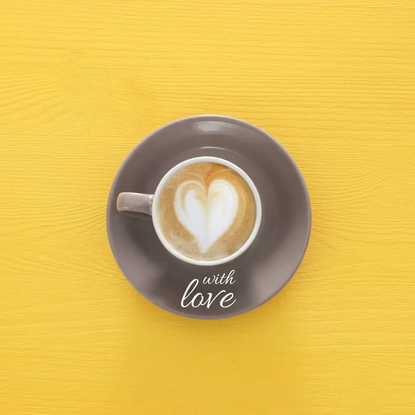 심장 모양 나무 노란색 배경 및 텍스트의 거품을 가진 커피 컵의 이미지: 사랑으로. — 스톡 사진