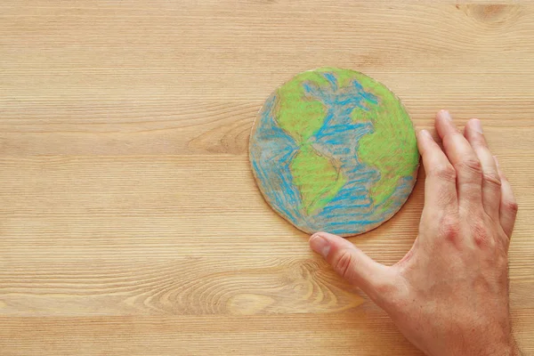 ahşap masa üzerinde dünya küre tutan adam el görüntüsünü üstten görünüm.