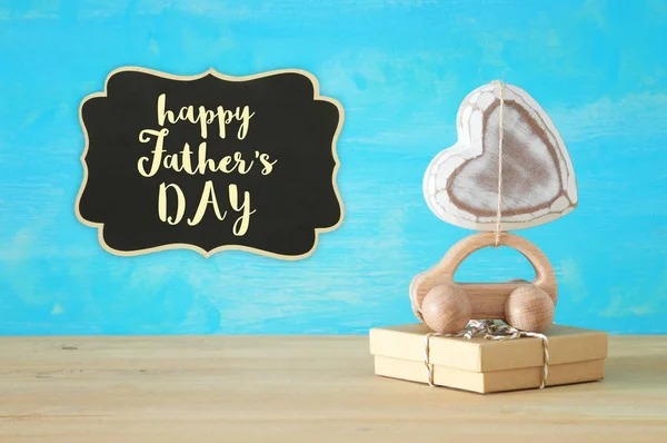 Image of wooden car over gift box and heart on the roof, present for dad. Father\'s day concept