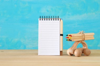 Geri okul kavramı. Yanındaki boş defter çatıda renkli kalemler ile ahşap oyuncak araba. Sahte için yukarı